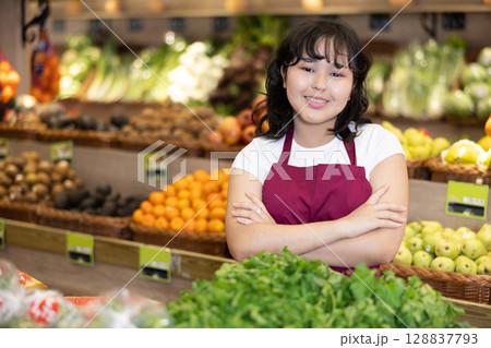 Portrait of friendly smiling female employee of grocery supermarket with parsley 128837793