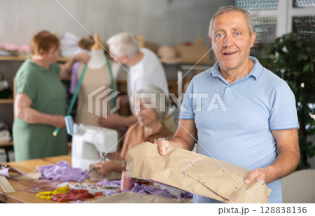 Elderly man with pattern at sewing master class Elderly man with pattern at sewing master class 128838136