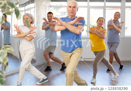 Woman participating in Zumba class for seniors in fitness studio 128838290