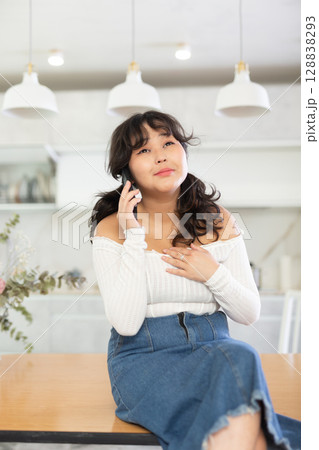Girl talking with friends on a smartphone while sitting on a table in room 128838293