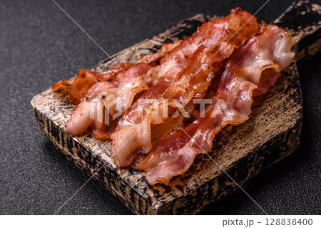 Cooked crispy bacon, slices of roast pork for an English breakfast. Fried bacon Cooked crispy bacon, slices of roast pork for an English breakfast. Fried bacon 128838400