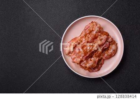 Cooked crispy bacon, slices of roast pork for an English breakfast. Fried bacon Cooked crispy bacon, slices of roast pork for an English breakfast. Fried bacon 128838414