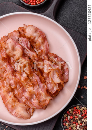 Cooked crispy bacon, slices of roast pork for an English breakfast. Fried bacon 128838425