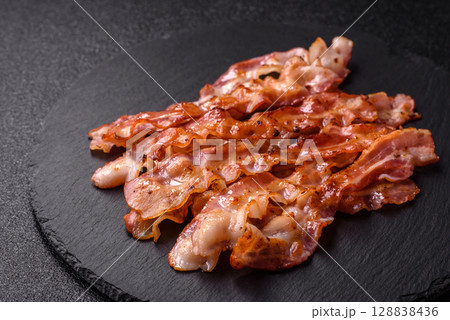 Cooked crispy bacon, slices of roast pork for an English breakfast. Fried bacon Cooked crispy bacon, slices of roast pork for an English breakfast. Fried bacon 128838436