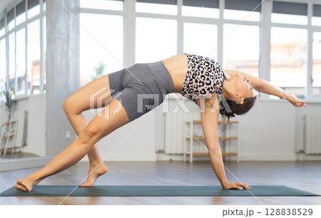 Sporty young girl performing powerful Camatkarasana yoga asana 128838529