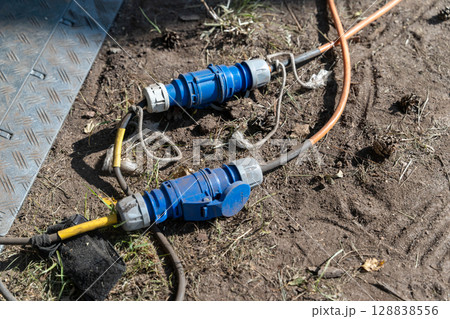 High voltage industrial electrical connectors lying on ground High voltage industrial electrical connectors lying on ground 128838556