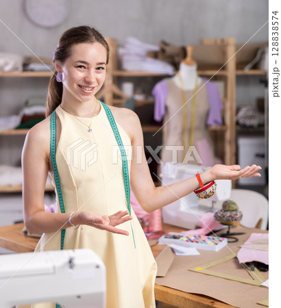 Young woman seamstress invites to sewing workshop Young woman seamstress invites to sewing workshop 128838574