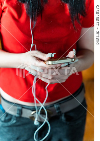 Young woman using smartphone and listening music with earphones Young woman using smartphone and listening music with earphones 128838575