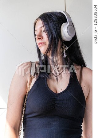 Young woman listening to music with wireless headphones and cross necklace Young woman listening to music with wireless headphones and cross necklace 128838634