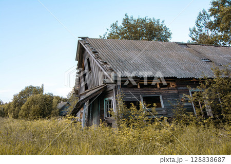 Abandoned wooden house crumbling in overgrown field Abandoned wooden house crumbling in overgrown field 128838687