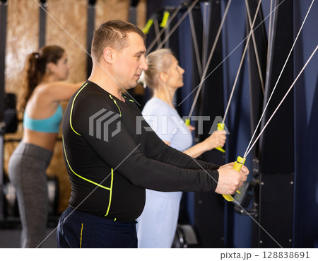 Sporty male athlete using skierg machine in gym Sporty male athlete using skierg machine in gym 128838691