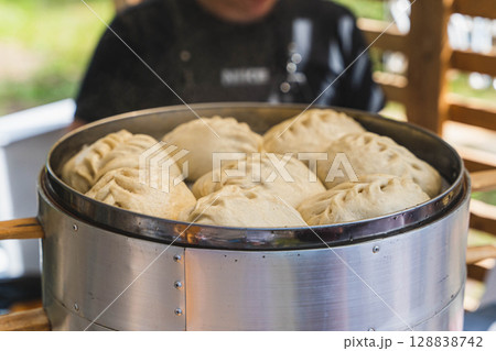 Steaming bao buns cooking in a metal pot at a street food market 128838742