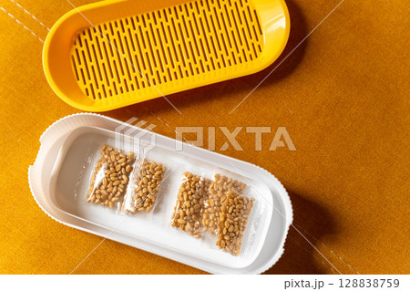 Wheatgrass growing kit with seeds and yellow strainer on orange background 128838759