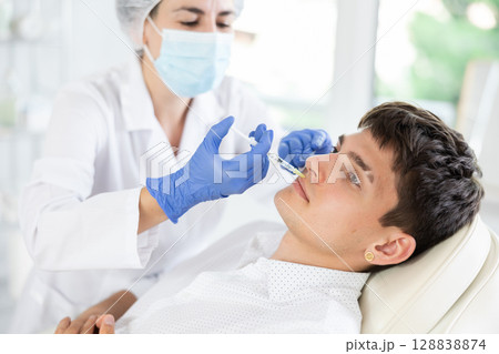 Young man having face care by means of injection in aesthetic clinic 128838874