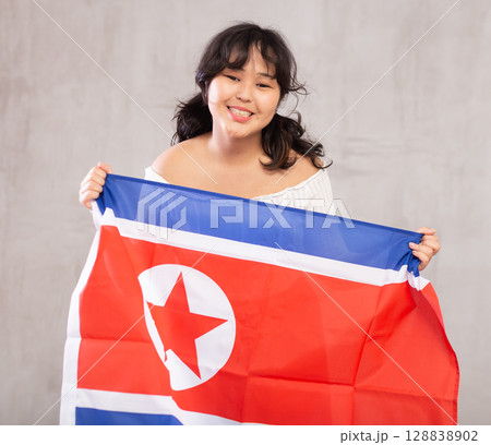 Smiling young girl holding North Korea flag Smiling young girl holding North Korea flag 128838902