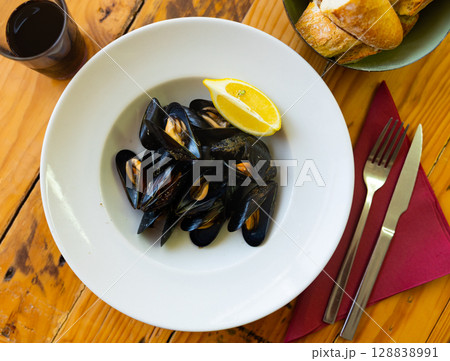 Picture of steamed tasty mussels served on pan with lemon 128838991
