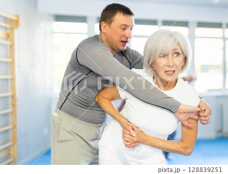 Old woman practicing self-defense techniques in pairs 128839251
