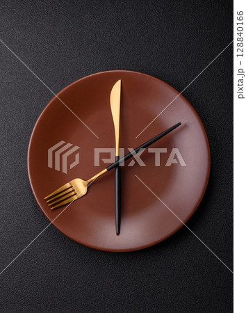 Empty plate with devices in the form of clock hands as a conceptual background for lunch time Empty plate with devices in the form of clock hands as a conceptual background for lunch time 128840166