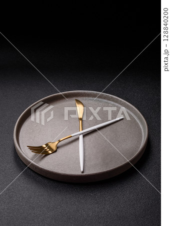 Empty plate with devices in the form of clock hands as a conceptual background for lunch time 128840200