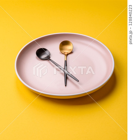 Empty plate with devices in the form of clock hands as a conceptual background for lunch time Empty plate with devices in the form of clock hands as a conceptual background for lunch time 128840223
