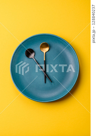 Empty plate with devices in the form of clock hands as a conceptual background for lunch time Empty plate with devices in the form of clock hands as a conceptual background for lunch time 128840237