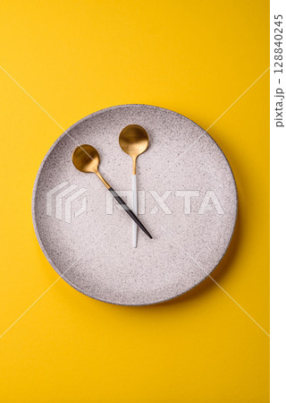 Empty plate with devices in the form of clock hands as a conceptual background for lunch time 128840245