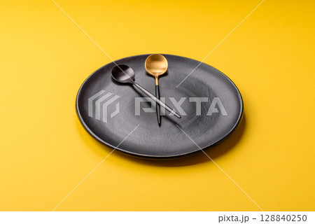 Empty plate with devices in the form of clock hands as a conceptual background for lunch time 128840250