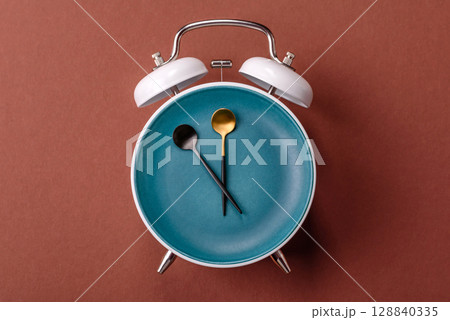 Empty plate with devices in the form of clock hands as a conceptual background for lunch time Empty plate with devices in the form of clock hands as a conceptual background for lunch time 128840335