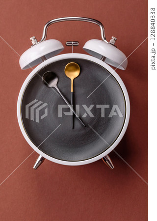 Empty plate with devices in the form of clock hands as a conceptual background for lunch time Empty plate with devices in the form of clock hands as a conceptual background for lunch time 128840338