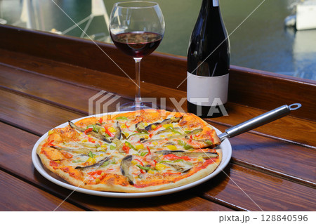 assorted pizza with different fillings: salami, tomatoes, mushrooms, bacon, sun-dried tomatoes. 128840596