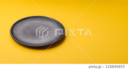 Empty round ceramic plate on yellow background. Food background 128840855