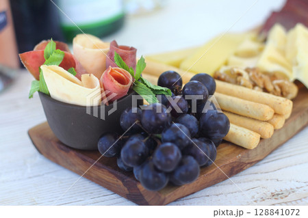 Italian charcuterie board featuring crackers cheese and salami served on wooden plank with raw bark edge 128841072