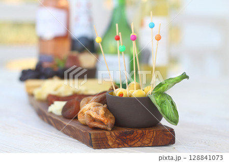 Italian charcuterie board featuring crackers cheese and salami served on wooden plank with raw bark edge 128841073