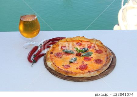 assorted pizza with different fillings: salami, tomatoes, mushrooms, bacon, sun-dried tomatoes 128841074