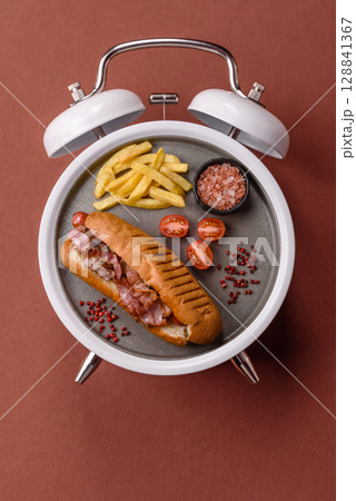 Hot dog, a sandwich with sausage, mustard, mayonnaise and ketchup . Concept of time to eat fast food 128841367
