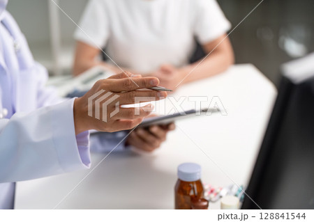 Healthcare professional explaining medication to a patient during consultation. 128841544