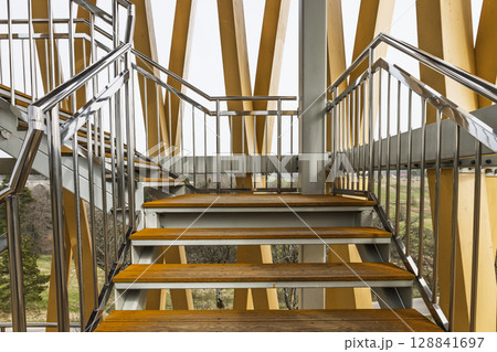 Upward perspective view of sustainable laminated wood stairway with sleek metal railings 128841697
