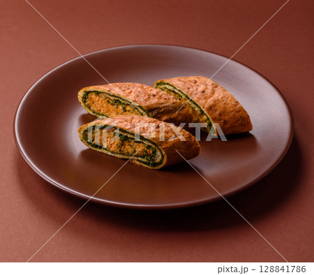 Roll of omelette, spinach, cheese and minced meat 128841786