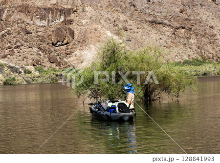 Fishing Adventure with a kayak on the Colorado River Surrounded by Rocky Cliffs 128841993
