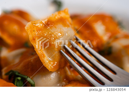 Fork lifting ravioli with tomato sauce from plate Fork lifting ravioli with tomato sauce from plate 128843054