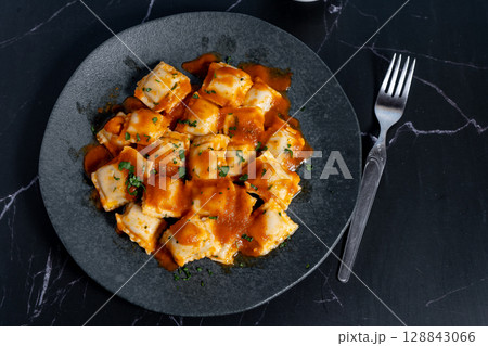 Ravioli pasta with tomato sauce and parsley on dark plate 128843066