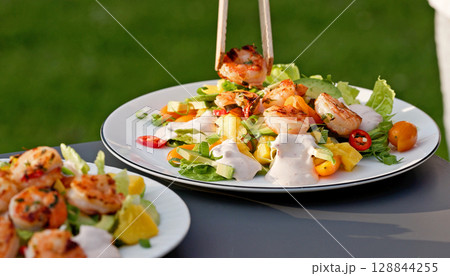 Chef put grilled shrimps on portion of freshly prepared healthy vegetable salad Chef put grilled shrimps on portion of freshly prepared healthy vegetable salad 128844255