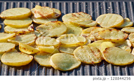 sliced potatoes with oil on hot grill pan 128844256