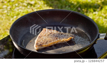 cook preparing fresh fish fillet on hot pan 128844257