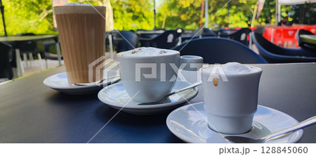 Three different types of coffee - espresso, cappuccino and latte - served outdoors in a cafe in Portugal. The concept of coffee culture and drink themes in the country. Three different types of coffee - espresso, cappuccino and latte - served outdoors in a cafe in Portugal. The concept of coffee culture and drink themes in the country. 128845060