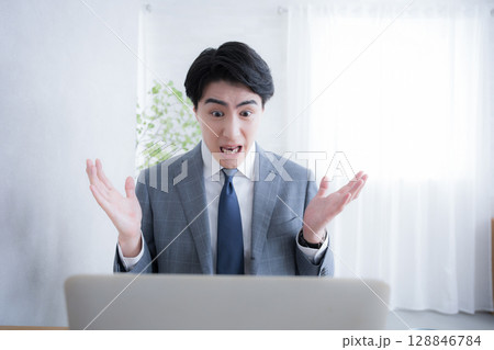 パソコンの前で仕事のお手上げポーズ　もうやってられない！ 128846784