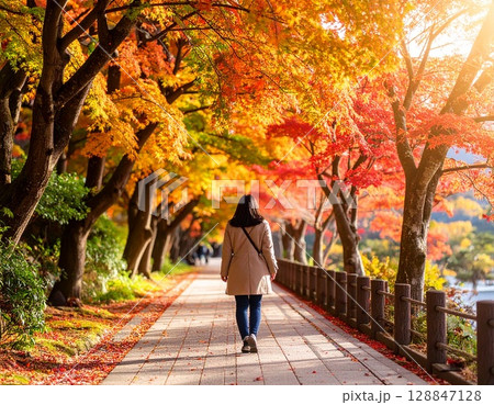 紅葉する並木道を歩く女性 128847128