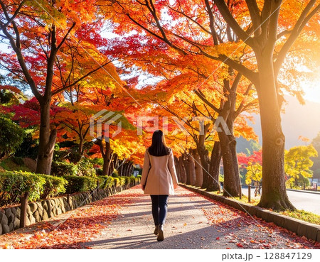 紅葉する並木道を歩く女性 128847129