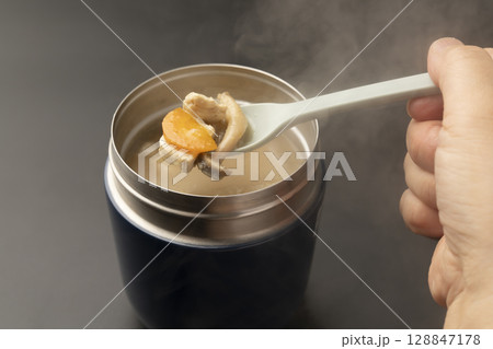 スープジャーに入れた冷めてない温かい味噌汁をスプーンで持ち上げる 128847178