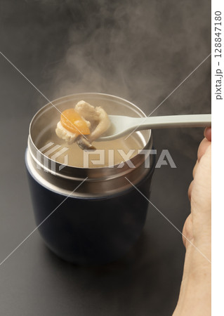 スープジャーに入れた冷めてない温かい味噌汁をスプーンで持ち上げる 128847180
